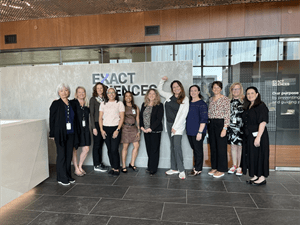 Exact Sciences team members and Patient Advocacy Advisory Council members pose for a group photo in front of the Exact Sciences logo.