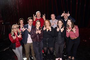 A group of Exact Sciences employees posing together holding up the letter W with their fingers for the University of Wisconsin