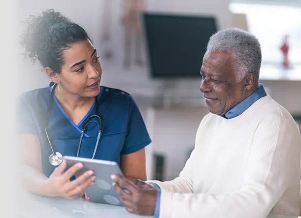 Healthcare provider reviewing information on a tablet with an older male patient.