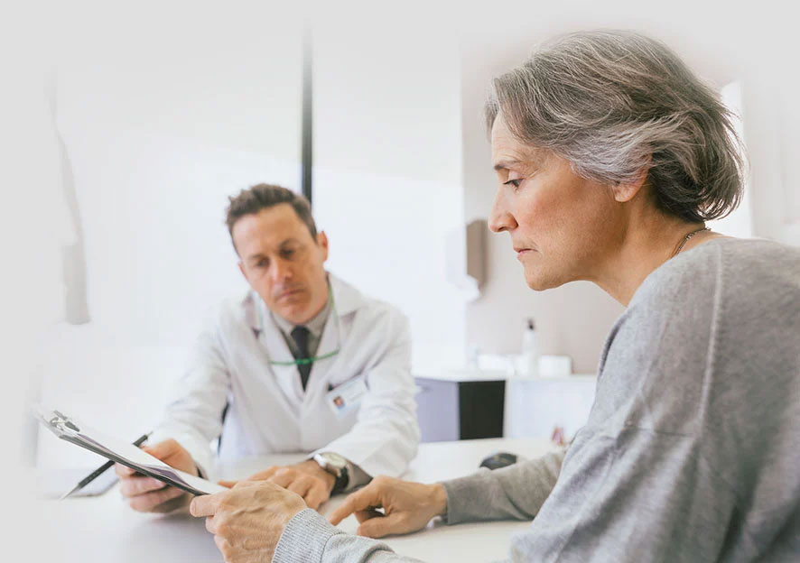Healthcare provider reviewing a document with a patient in an exam room.