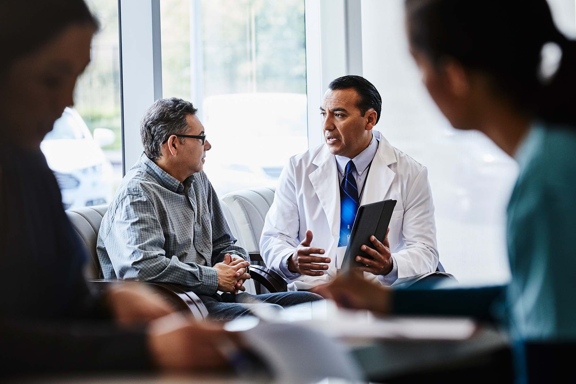 Healthcare provider speaking with a patient in a waiting area.
