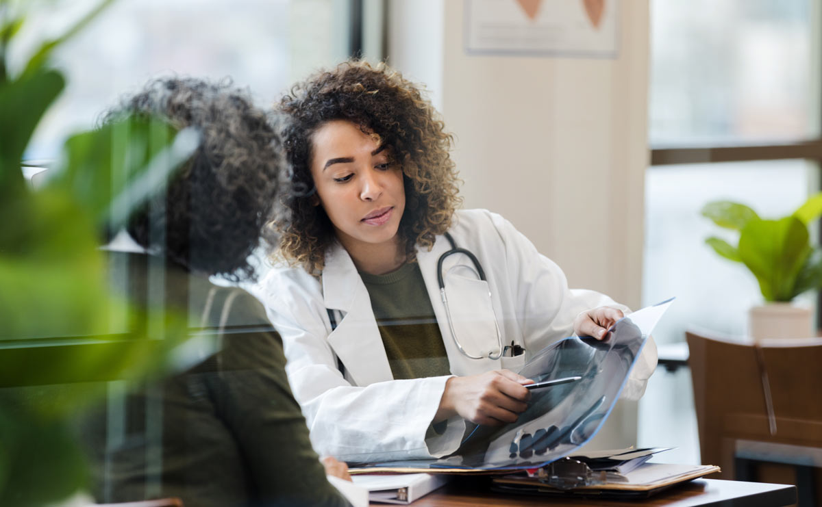 Healthcare provider discussing information at a desk with a patient.