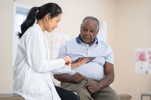 Healthcare provider reviewing information on a tablet with a patient during an office visit