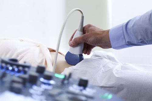 Healthcare provider performing an ultrasound examination on a patient, illustrating an example of hepatocellular carcinoma surveillance
