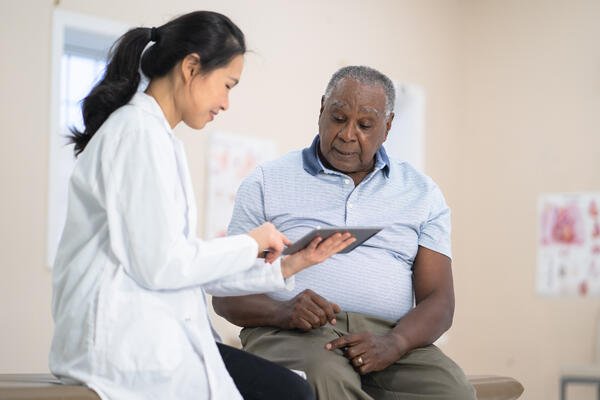Healthcare provider reviewing information on a tablet with a patient during an office visit