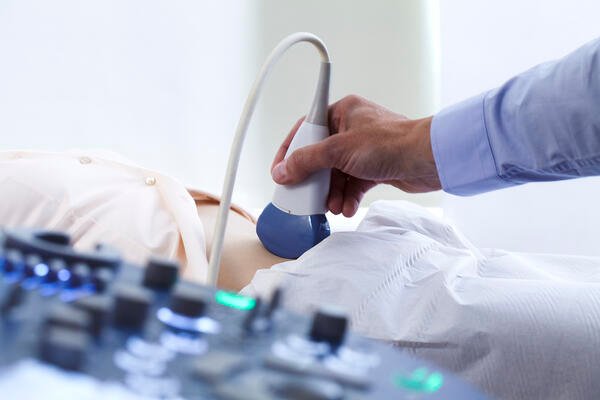 Healthcare provider performing an ultrasound examination on a patient, illustrating an example of hepatocellular carcinoma surveillance