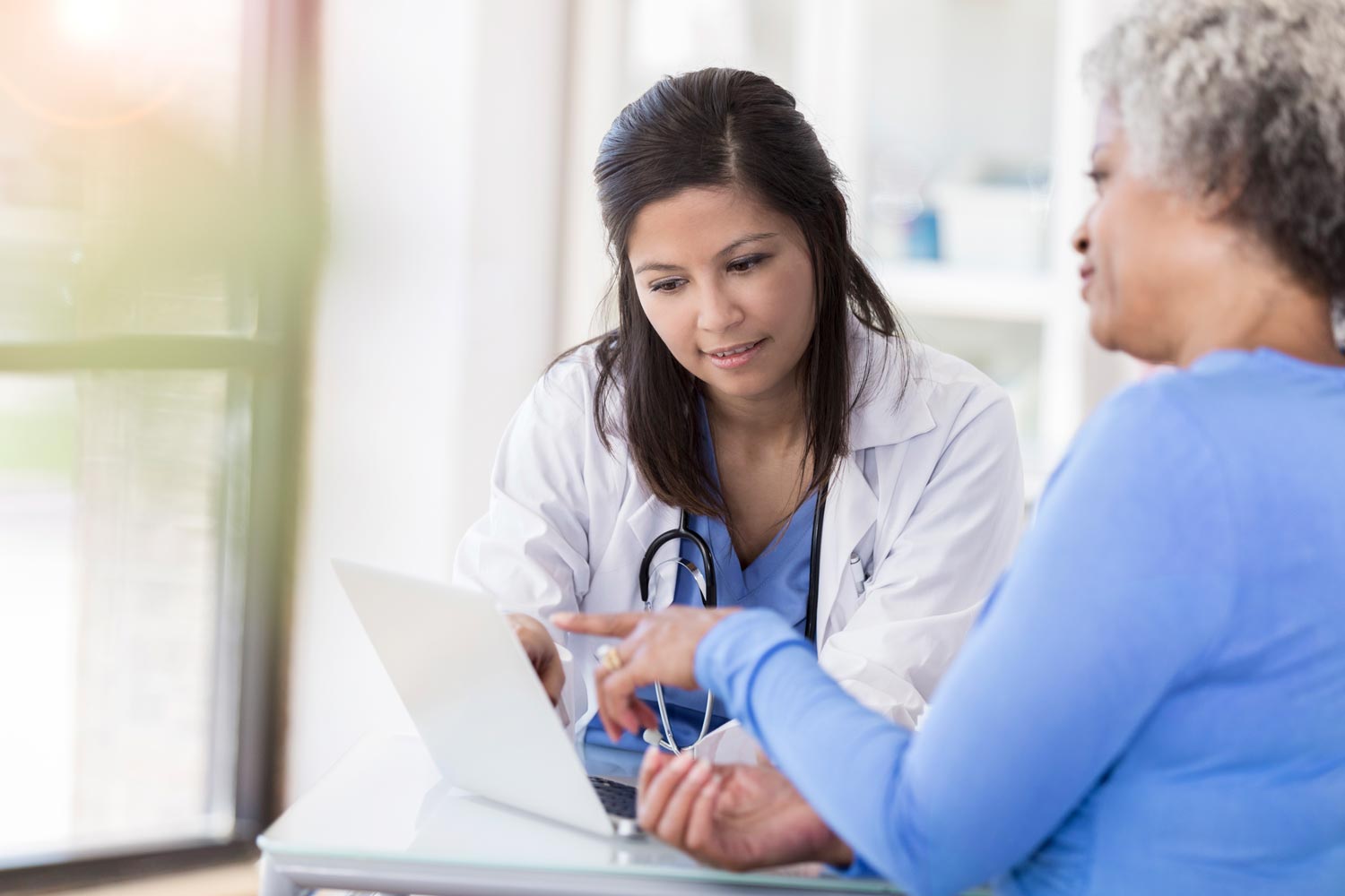 Healthcare provider reviewing information on a laptop with a patient.